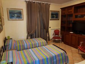 Schlafzimmer mit einem Bett, einem TV und einem Stuhl in der Unterkunft B&B Villa Elema in Nettuno