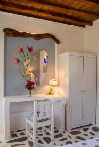 a white dressing table with a mirror and a white chair at Lakki Village in Aegiali
