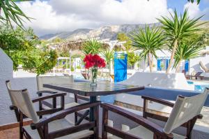 a table and chairs with a vase of flowers on a patio at Lakki Village in Aegiali