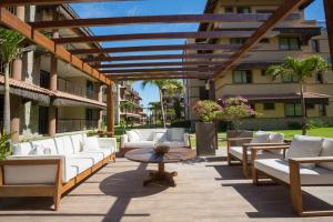 un patio con divani bianchi, un tavolo e un edificio di Manhattan Beach Riviera ad Aquiraz