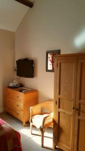 um quarto com uma cama, uma cómoda e uma televisão em The Oak at Dewlish em Dorchester