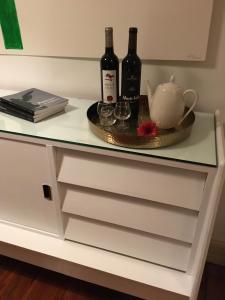 - une commode blanche avec 2 bouteilles de vin dans l'établissement Hotel Jardim, à Coimbra