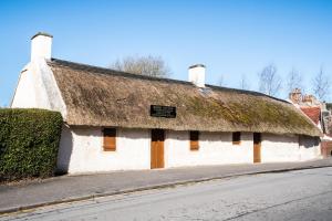 an old white building with a grass roof at No5 Ayr Beach - Coorie Doon Stays in Ayr