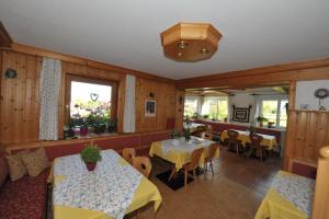un restaurant avec deux tables, des chaises et des fenêtres dans l'établissement Haus Helga, à Mauterndorf