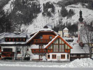 un bâtiment avec de la neige devant une montagne dans l'établissement Haus Helga, à Mauterndorf