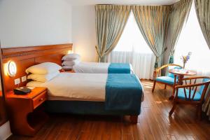 Cette chambre d'hôtel comprend deux lits, une table et des chaises. dans l'établissement City Inn Palace Hotel, à Ramallah