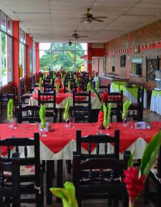 a restaurant with red tables and chairs with green flowers at Hotel Campestre Los Tucanes in Armenia +74 photos