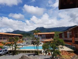 un complexe avec une piscine et des montagnes en arrière-plan dans l'établissement Condomínio Ville II, à Ubatuba