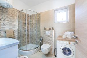 a bathroom with a shower toilet and a washing machine at Apartman Tea in Privlaka +32 photos