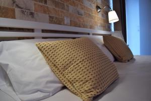 a bed with two pillows and a brick wall at The Coast seaside rooms in Anaxos