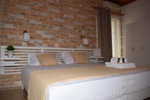1 dormitorio con 1 cama grande y pared de ladrillo en The Coast, en Anaxos