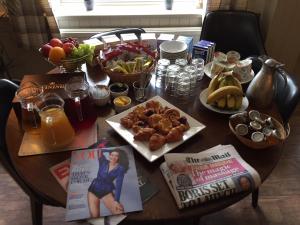 una mesa de madera con comida y revistas. en The Black Swan Inn, en Norwich