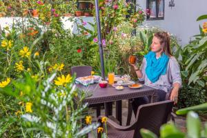 a woman sitting at a table in a garden at Hostal Riviera Sucre in Otavalo