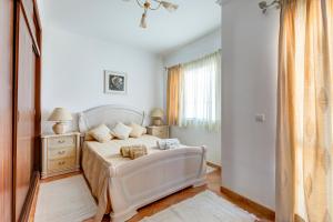a bedroom with a white bed and a window at Bougainvilleas Villa - Private Pool and Parking, Nearby Beach in Altura