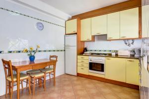a kitchen with yellow cabinets and a table and chairs at Bougainvilleas Villa - Private Pool and Parking, Nearby Beach in Altura