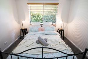 1 dormitorio con cama con almohadas y ventana en Armidale Cottage - House 2, en Armidale