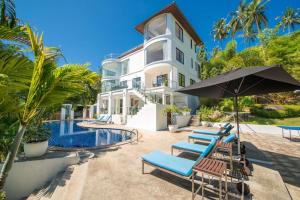 a building with chairs and an umbrella next to a pool at White Stone - Luxurious Sunset View 4 Bed Pool Villa in Nathon