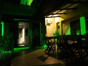 um quarto escuro com uma mesa e cadeiras e luzes verdes em Pousada da Família em Araranguá