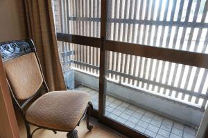 una silla sentada frente a una ventana con persianas en Ichijyo Ivy en Kioto