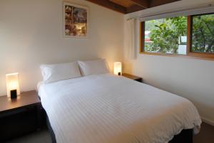 a bedroom with a white bed with two lamps and a window at Chris's Beacon Point Restaurant & Villas in Apollo Bay