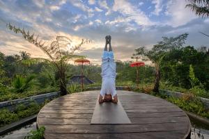 a person doing a handstand on a wooden table at Nau Villa Ubud in Tegalalang