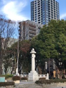 a monument in a park in front of a tall building at Kuretake Inn Nagoya Hisayaodori in Nagoya