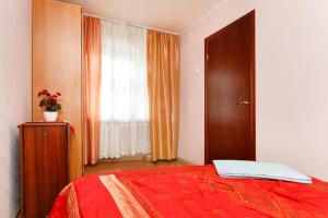 a bedroom with a red bed and a window at Apartments on Chelyuskintsev in Yekaterinburg