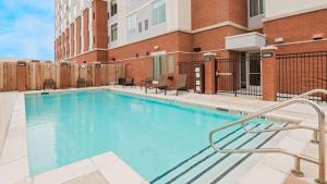 a swimming pool with chairs and a building at Hyatt Place Austin/Round Rock in Round Rock