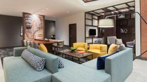 una sala de estar con sofás azules y sillas amarillas. en Hyatt Place Austin/Round Rock en Round Rock