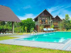 a villa with a swimming pool in front of a house at Roo Mansala Boutique Villas in Sigiriya
