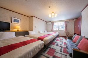 a hotel room with two beds and a couch at Rosenheim Hakuba in Hakuba