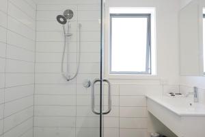 a white bathroom with a shower and a sink at Stopforths Motel in Hokitika
