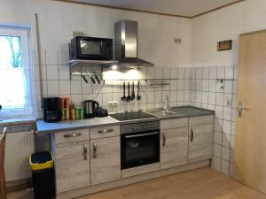 a kitchen with a stove and a microwave at Gästehaus Katharina in Müllenbach