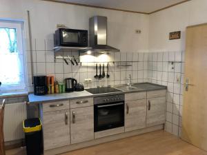 eine Küche mit einem Herd und einer Mikrowelle in der Unterkunft Gästehaus Katharina in Müllenbach