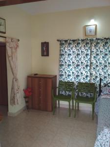 a bedroom with two chairs and a dresser in a room at Noel Guest House in Marmagao