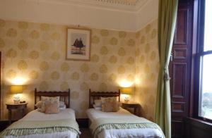two beds in a room with two windows at Hillcrest House in Wigtown