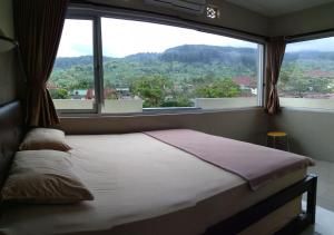 a bed in a room with a large window at Tirta Kencana Baturraden in Baturaden