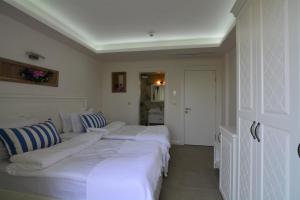 a row of white beds in a room at Dalyan Risus Suite in Çeşme