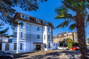 a large white building with a palm tree at Connaught Lodge in Bournemouth