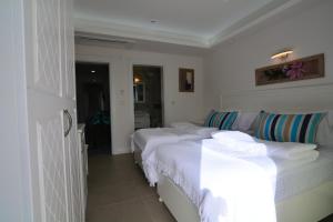 a bedroom with three beds with white sheets at Dalyan Risus Suite in Çeşme