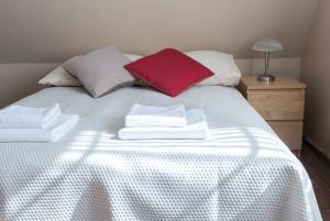 a bed with white towels and a red pillow at Villa Stratus in Gdańsk