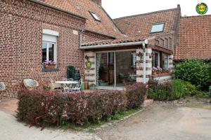 ein Backsteinhaus mit einem Tisch, Stühlen und Blumen in der Unterkunft La ferme de la vallée in Auchy-au-Bois