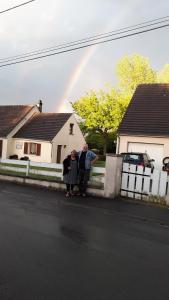 Ein Mann und eine Frau stehen neben einem Zaun mit Regenbogen in der Unterkunft Le Mouton Blanc in Couloisy