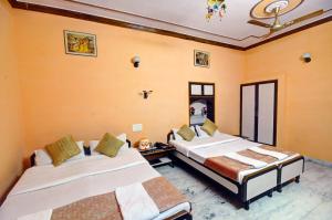 ジャイサルメールにあるHotel Jaisal Palaceのオレンジ色の壁の部屋にベッドが2つある