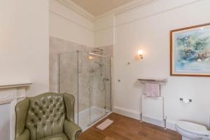 a bathroom with a shower and a chair and a toilet at Blervie House in Forres