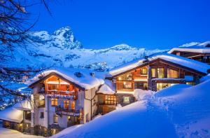 a house in the snow at night with mountains at Saint Hubertus Resort in Breuil-Cervinia