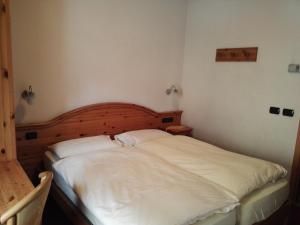 a bed with a white bedspread and pillows at Garni Baita Cecilia in Livigno