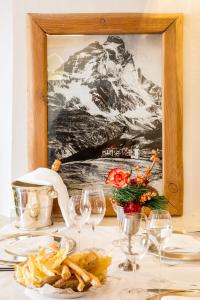 a table with wine glasses and a picture of a mountain at Saint Hubertus Resort in Breuil-Cervinia