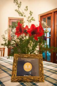una foto di un vaso con fiori rossi su un tavolo di Royal Wattles a Nuwara Eliya