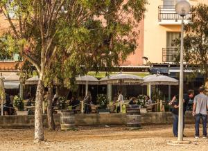 a group of people sitting at a restaurant with umbrellas at Hôtel Le Porquerollais in Porquerolles